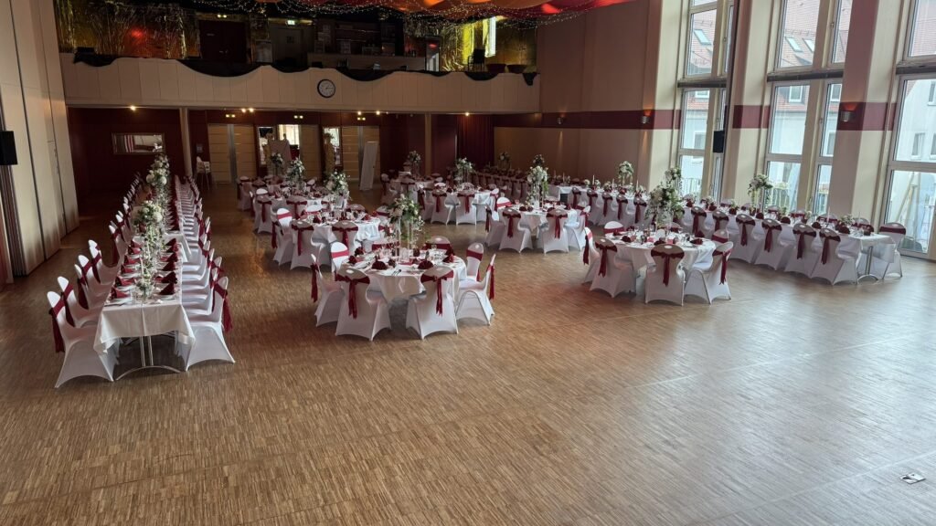 Hochzeitstafeln mit weißen Hussen im Festsaal des Kolpinghauses Regensburg