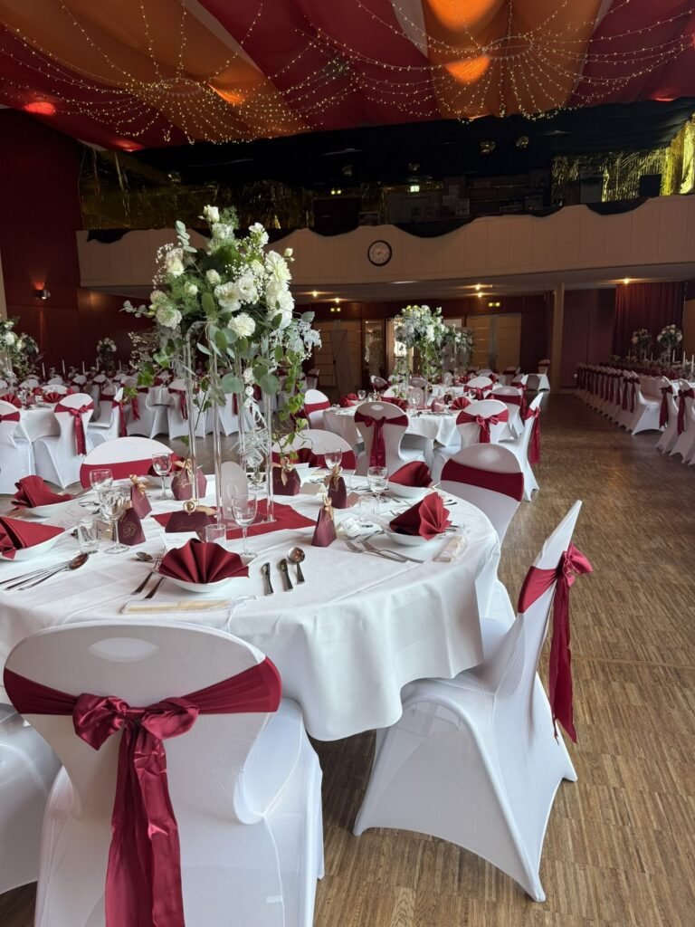 Hochzeitstisch mit Blumenschmuck und roten Schleifen im Kolpinghaus Regensburg