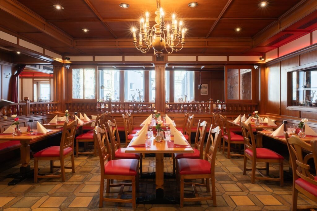 Holzvertäfelte Gaststube des Restaurant St. Erhard in Regensburg mit Kronleuchter und eingedeckten Tischen