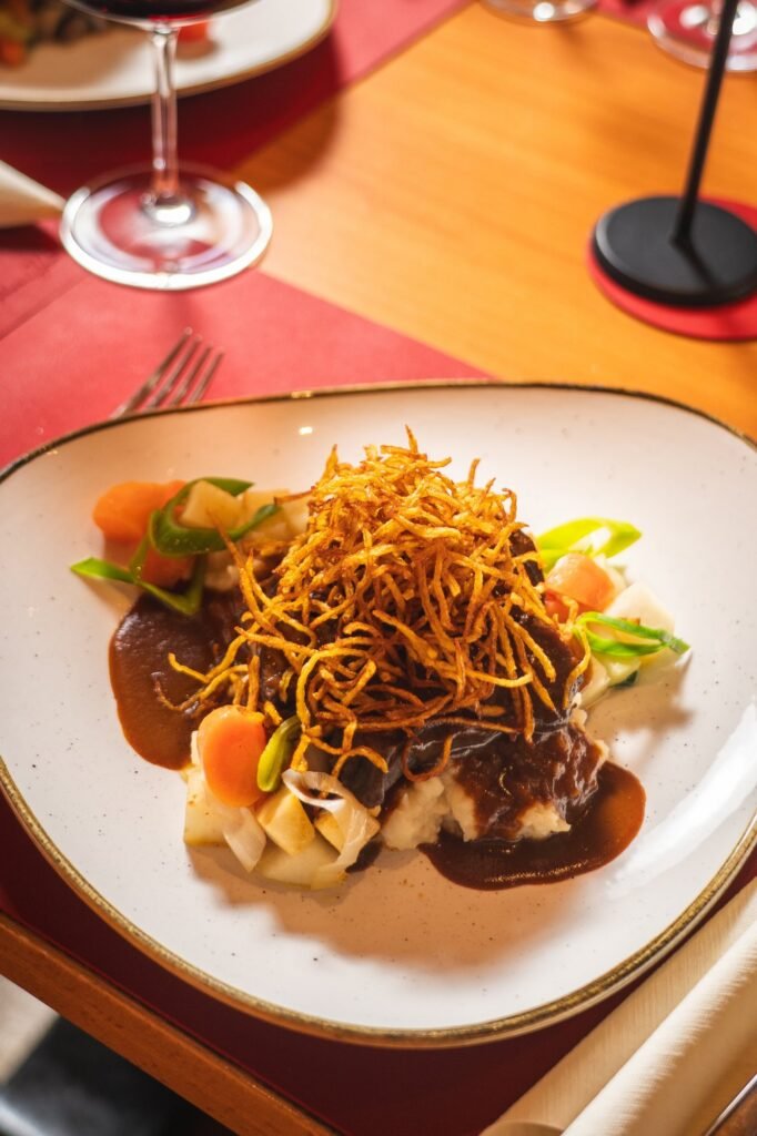 Geschmortes Fleisch mit Soße, Röstzwiebeln und Gemüse aus der Küche des Restaurant St. Erhard Regensburg